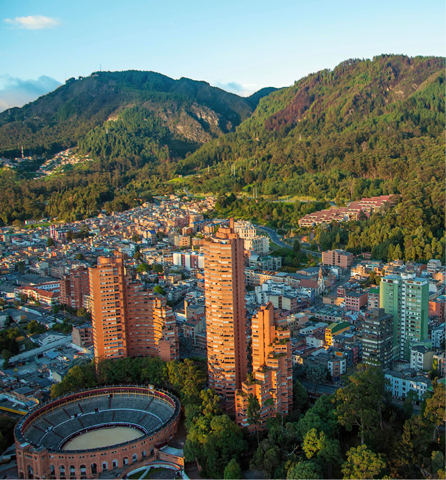 aerial view of a city, with an arena, with mountains in the background