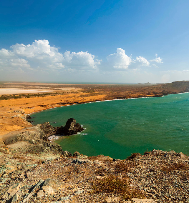 aerial shot of a coastal bay with red sand and turquoise water 