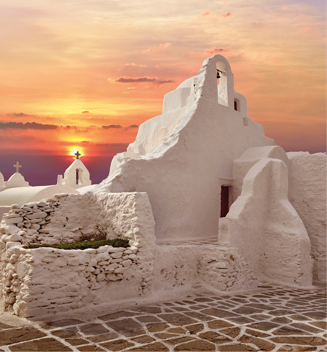 White church building with stoned foothpath infront of a bright red, pink and orange sunset