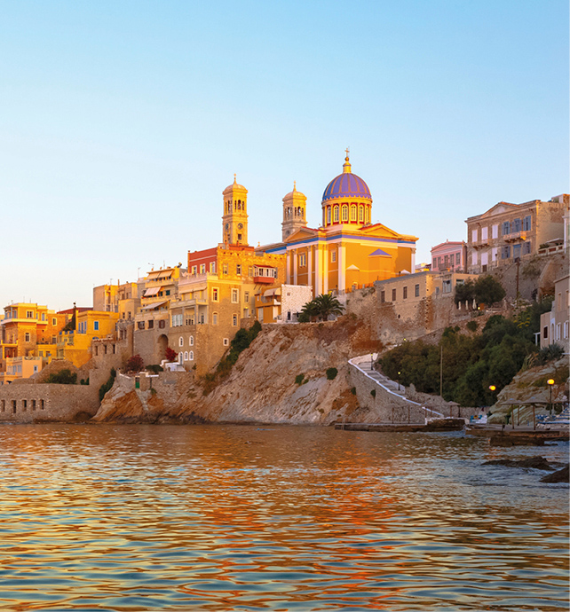 City on top of a cliff overlooking the water at sunset 