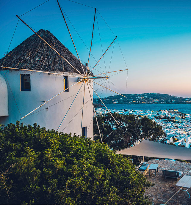 windmill at the top of a hill overlooking a bay at night time 