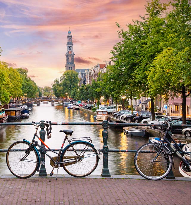 a bridge over a canal in Amsterdam with buildings, boats and bicycles