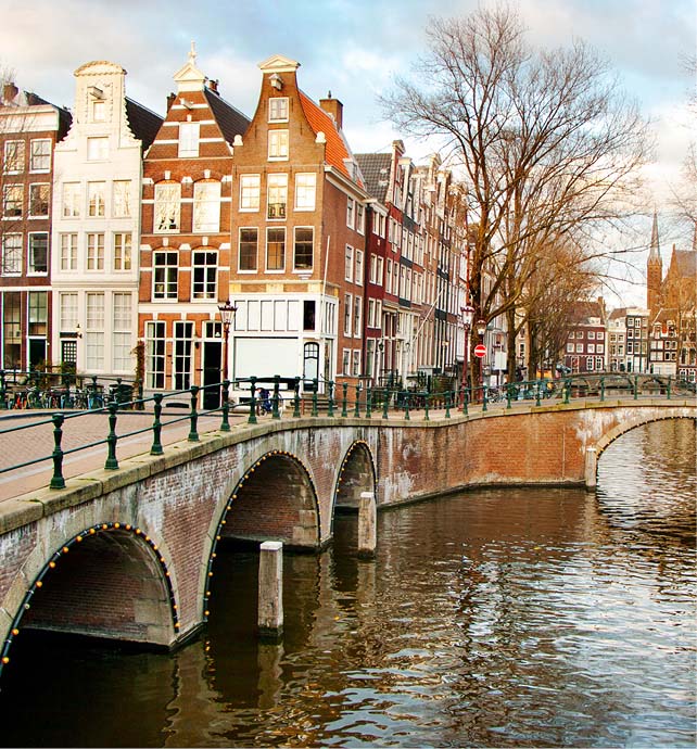 a bridge over a canal in Amsterdam with buildings and trees