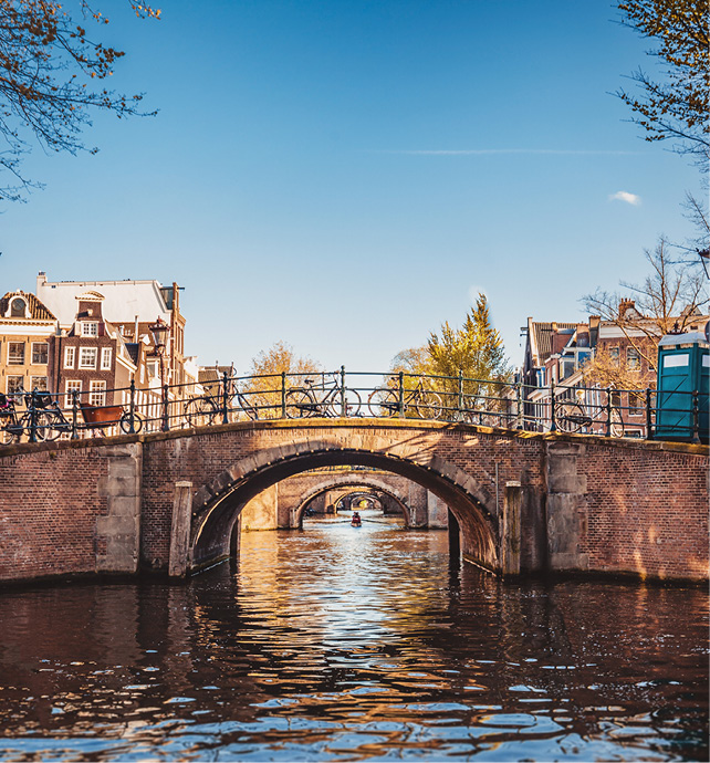 a bridge over a canal in Amsterdam with buildings and a boat