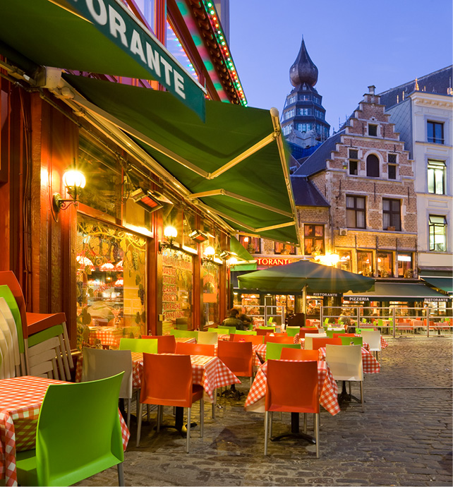 outdoor seating area on the street at an italian restaurant with red and green chairs with tables covered in red and white gingham tablecloths