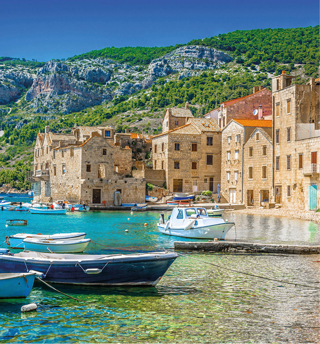  Clear waters with small boats tied to the shores of a stone beach in Vis, Croatia