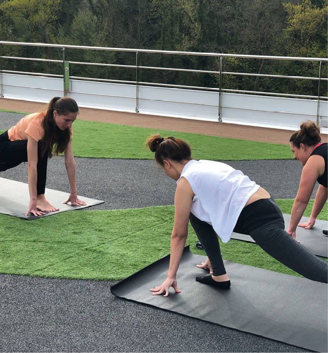 Morning yoga session on the top deck of a cruise ship, with a wellness coach and two guests 