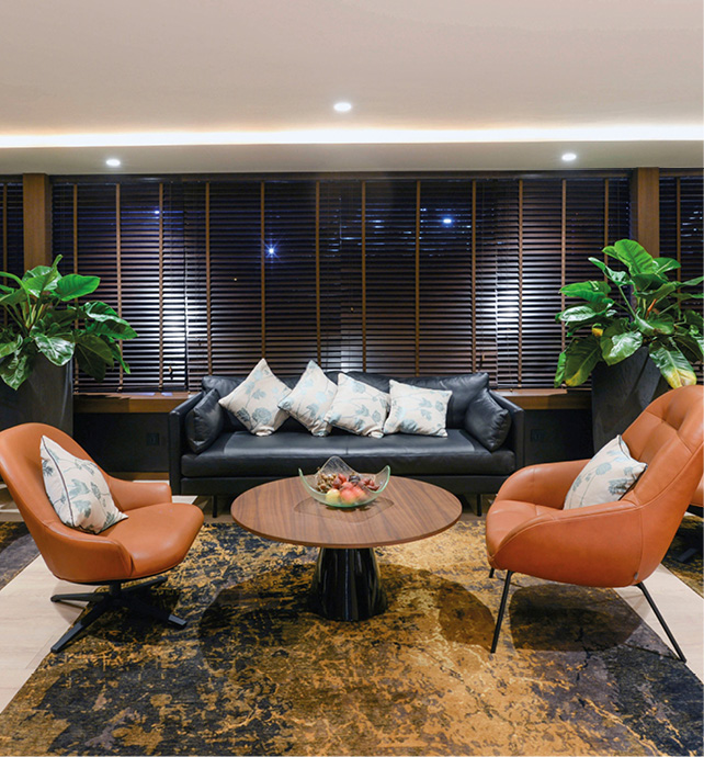 Comfortable brown chairs around wooden tables with blue sofa and Asian-inspired décor in the Lotus Lounge